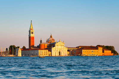 View of buildings by sea against clear sky