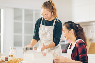 Young woman holding food while standing on table