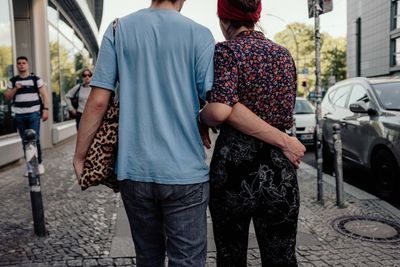 Rear view of people walking on street in city