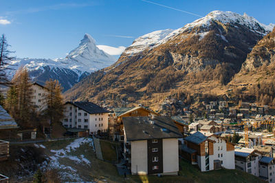 Houses by snowcapped mountain against sky