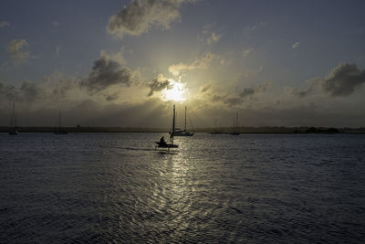 Silhouette sailboat in sea against sky during sunset