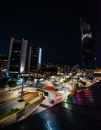 High angle view of illuminated street amidst buildings in city at night
