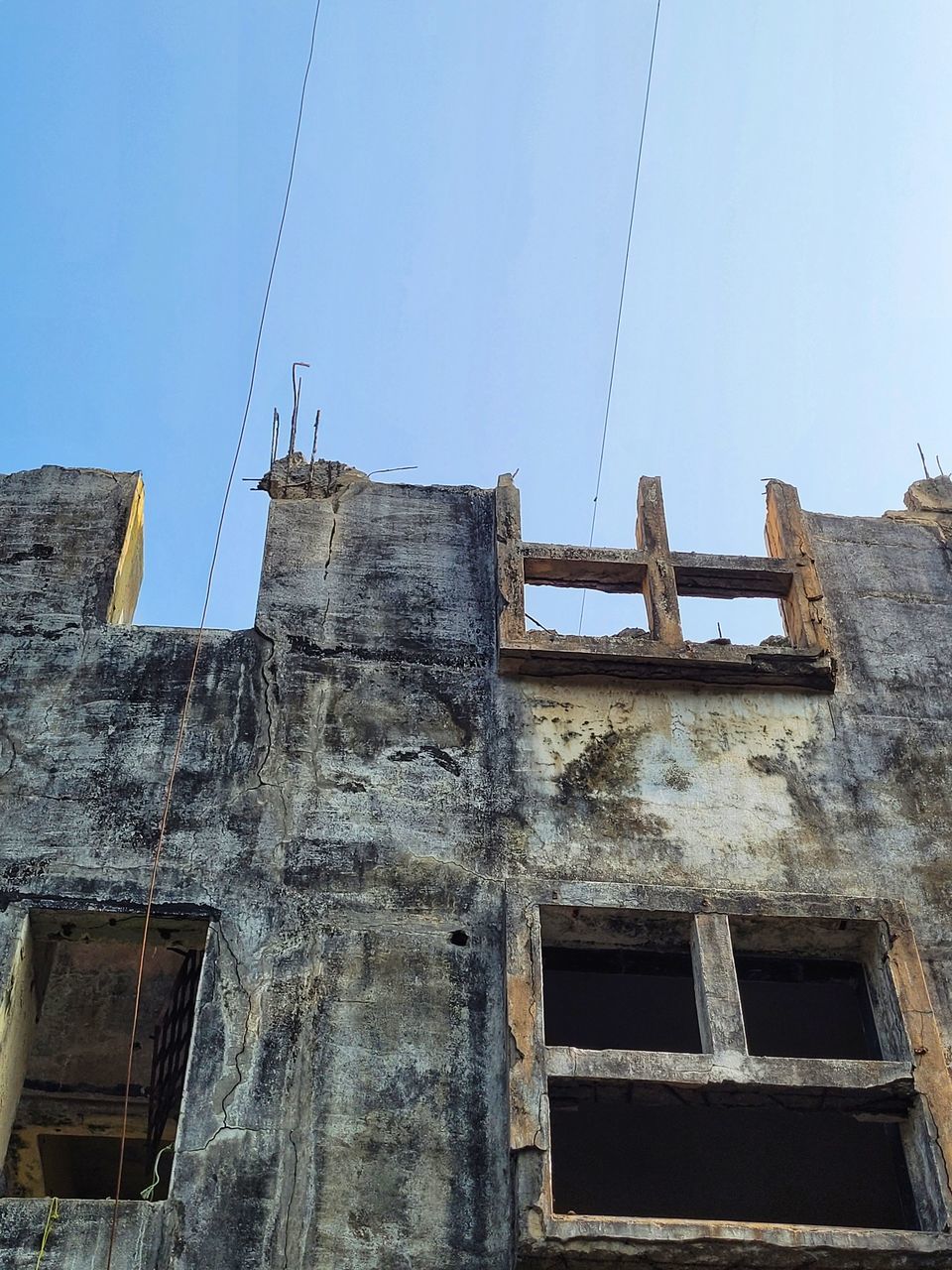 architecture, built structure, building exterior, sky, low angle view, building, no people, wall, history, clear sky, old, nature, house, window, day, ruins, the past, ancient history, roof, facade, outdoors, blue, abandoned, residential district, urban area, industry