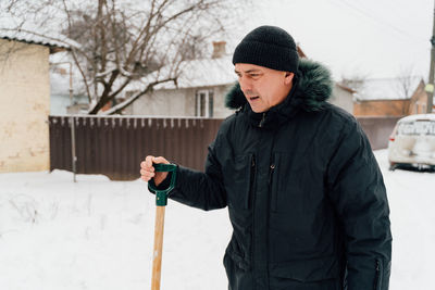 Snow collapse. senior man cleaning snow at winter weather with a shovel on a yard 