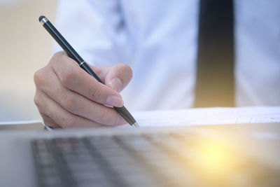 Close-up of hand holding pen on table