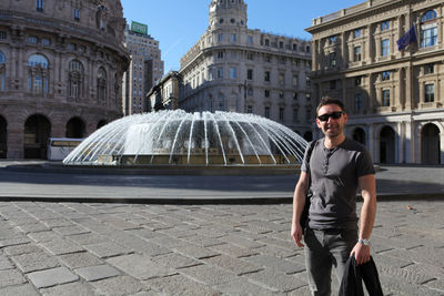 Portrait of smiling man with fountain in city