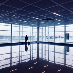 Silhouette man standing by window in airport lobby