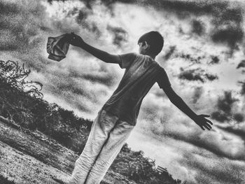 Low angle view of man holding umbrella against sky