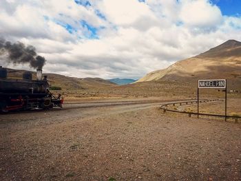 Road by mountains against sky