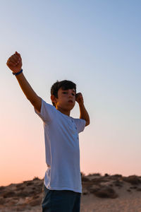 Full length of boy standing on beach against sky during sunset