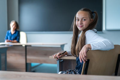 Young woman using mobile phone while sitting at cafe