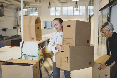 Businesswomen moving cardboard boxes into new office