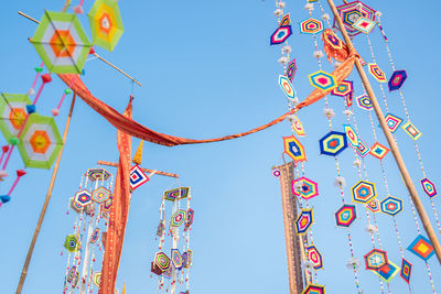 Low angle view of lanterns hanging against clear blue sky