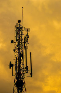 Low angle view of communications tower against orange sky