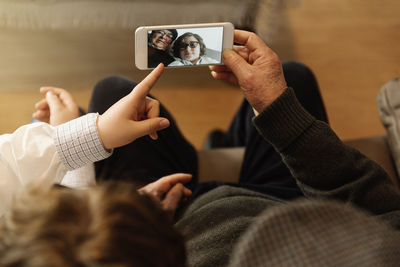 High angle view of couple looking at photograph on smart phone