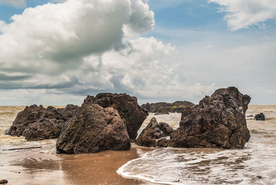 Rock formations on shore against sky