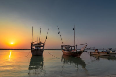 Sailboat moored on sea against sky during sunset