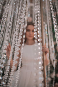 Portrait of young woman standing against blurred background