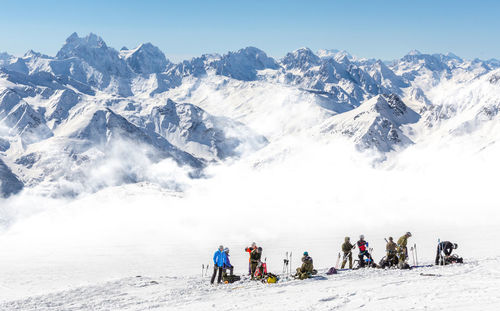 People on snowcapped mountain against sky