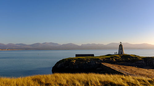 Lighthouse by sea against sky