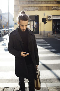 Man using mobile phone while standing on city street