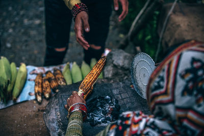 High angle view of woman roasting corn on barbeque for customer