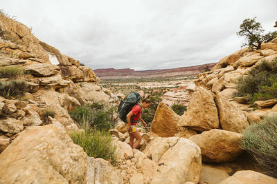 Female backpacker hikes over rocky rugged terrain in utah desert