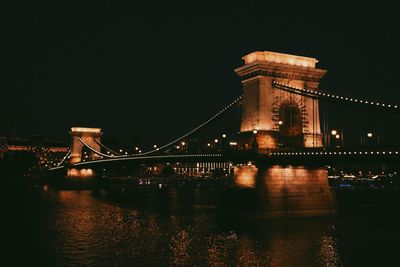 Illuminated bridge over river at night