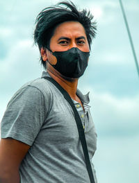 Portrait of man wearing masker standing against sky