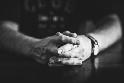 Close-up of man hands clasped on table