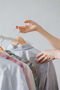 A woman's hand holds a hanger with clothes in the wardrobe. recycling. stylist or merchandiser