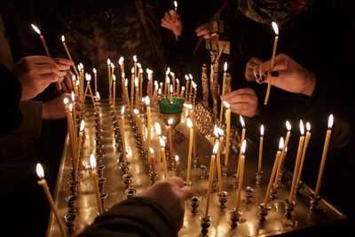 Low angle view of hands holding candles in temple