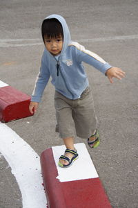 Portrait of cute boy walking on concrete block