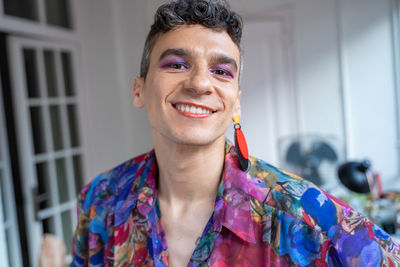 Portrait of confident transgender man in casual sitting on sideboard at home