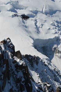 Scenic view of snowcapped mountains against sky with rescue helicopter