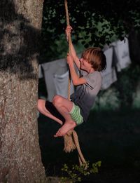 Full length of boy holding tree trunk