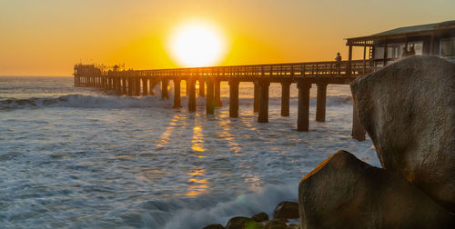 Pier over sea against sky during sunset