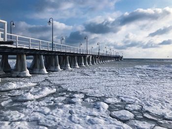 Bridge over sea against cloudy sky