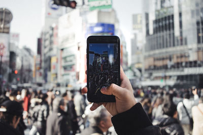 Close-up of hand holding mobile phone in city