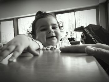 Portrait of happy girl holding table at home