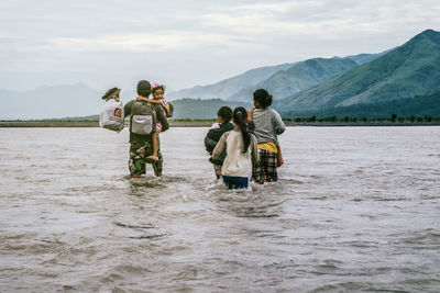 Rear view of people on mountain against sky