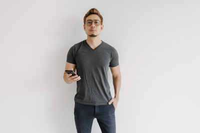 Portrait of young man standing against white background
