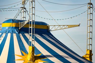 Low angle view of circus tent against blue sky