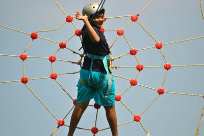 Portrait of girl climbing on jungle gym against clear sky