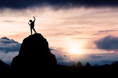 Silhouette man standing on mountain against sky during sunset