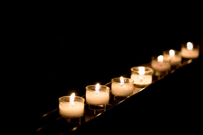 Close-up of lit candles in darkroom