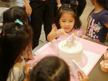 Girl looking at cake on table during birthday