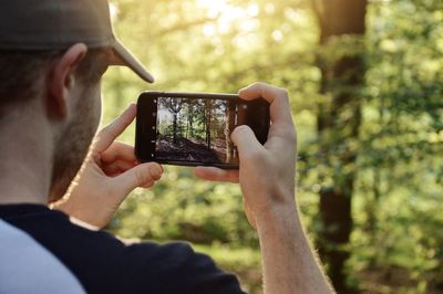 Midsection of man photographing nature in the evening with mobile phone 