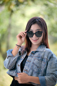 Portrait of young woman wearing sunglasses while standing outdoors