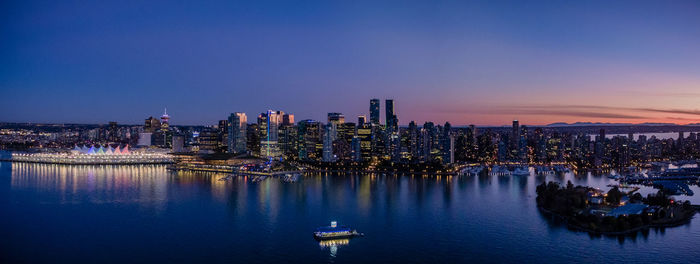 River by cityscape against sky at dusk